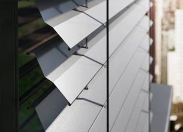 Raffstore mit verstellbaren Aluminiumlamellen vor einem Fenster